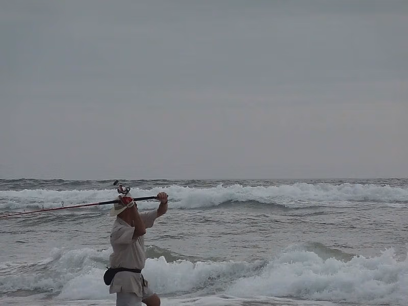 Pêcheur pratiquant le surfcasting dans les vagues de l’océan Atlantique sur une plage d’Iguéla au Gabon.