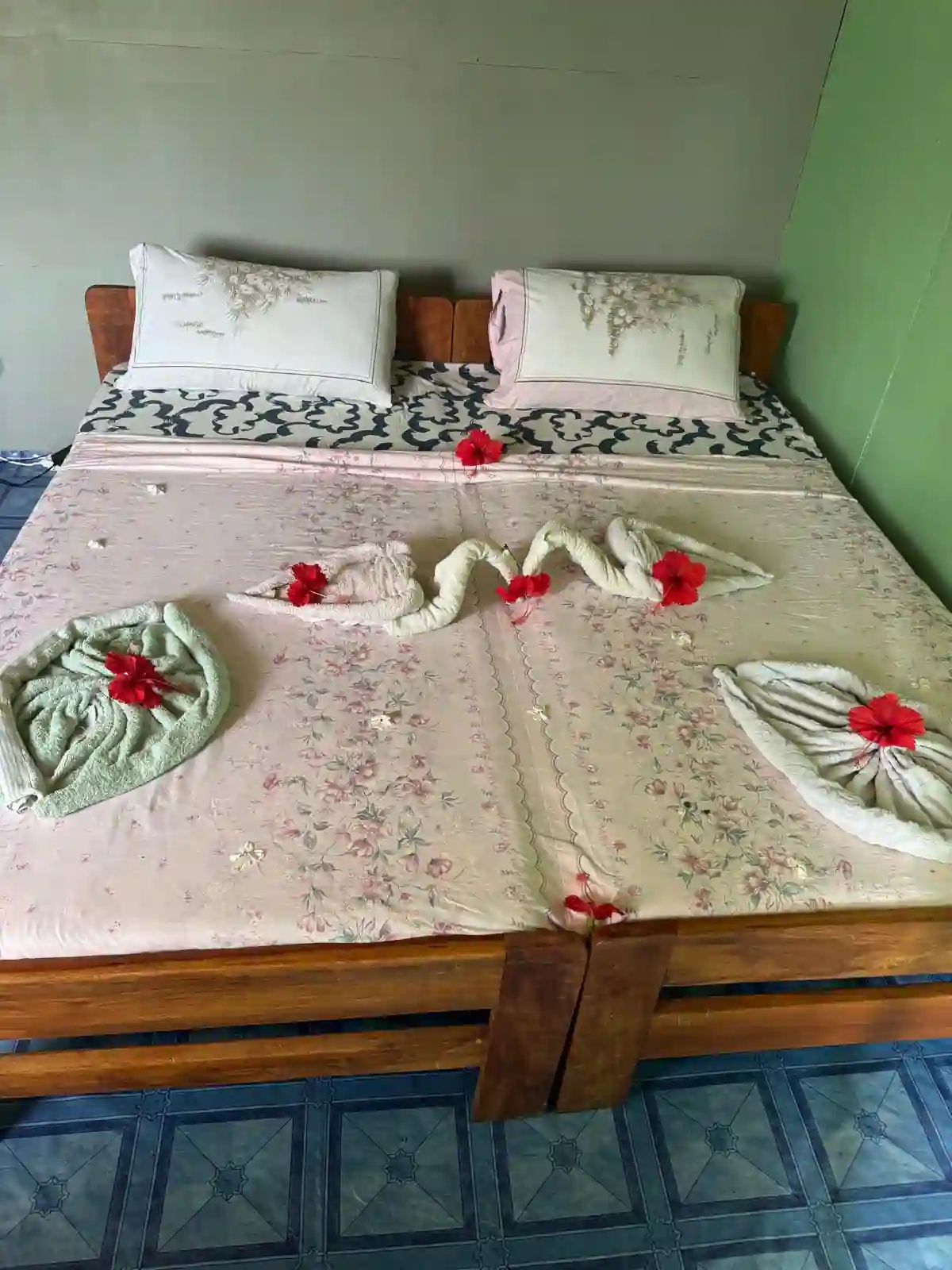Lit double préparé avec serviettes décoratives et fleurs tropicales dans un hébergement de Bangué Lodge au Gabon.