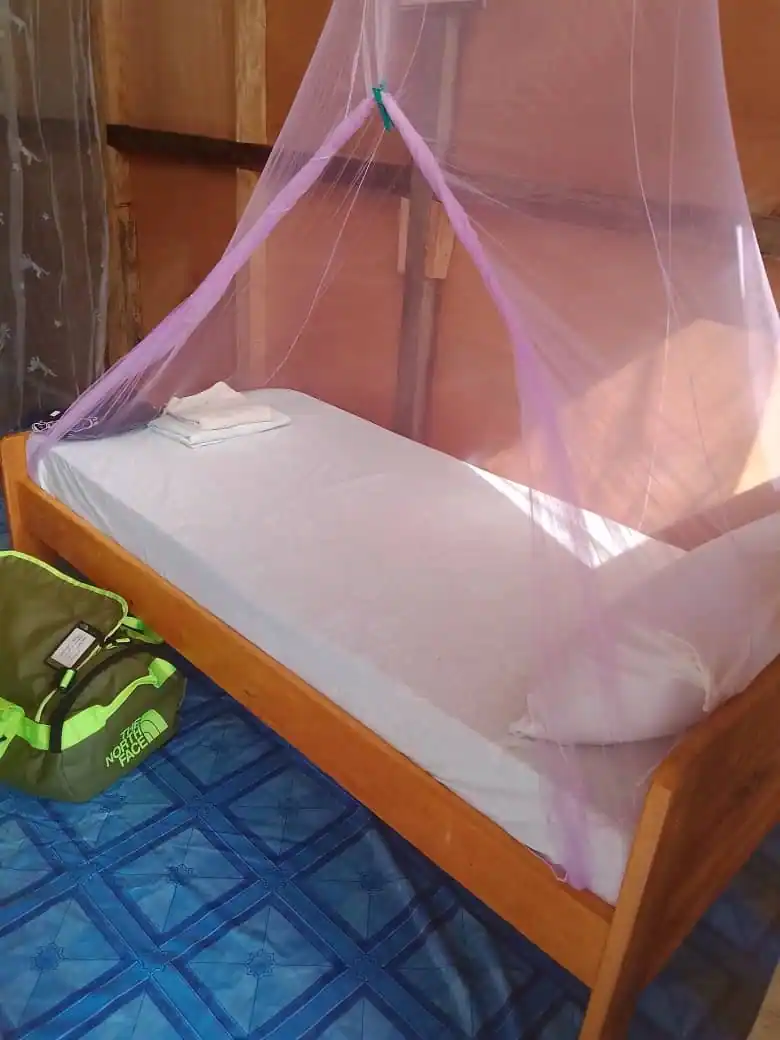 Lit avec moustiquaire dans un bungalow de Bangué Lodge, conçu pour un séjour confortable au bord de la lagune d’Iguéla.