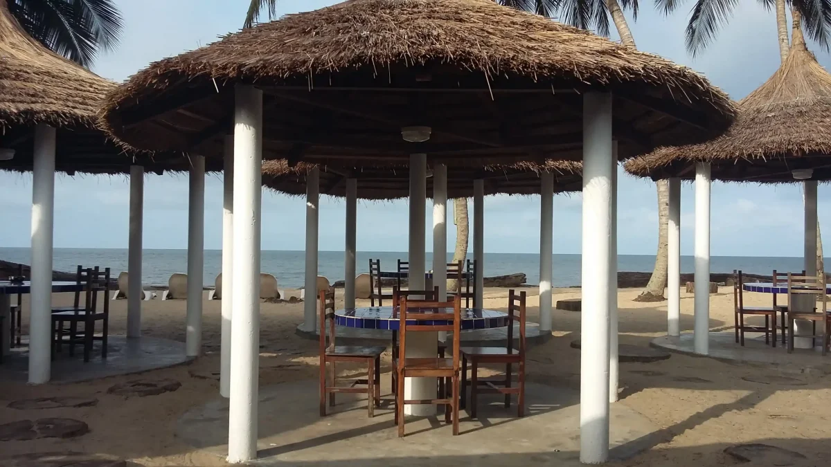 Restaurant de plage Tropicana avec paillotes traditionnelles, tables en bord d’océan et ambiance tropicale sur la côte gabonaise.