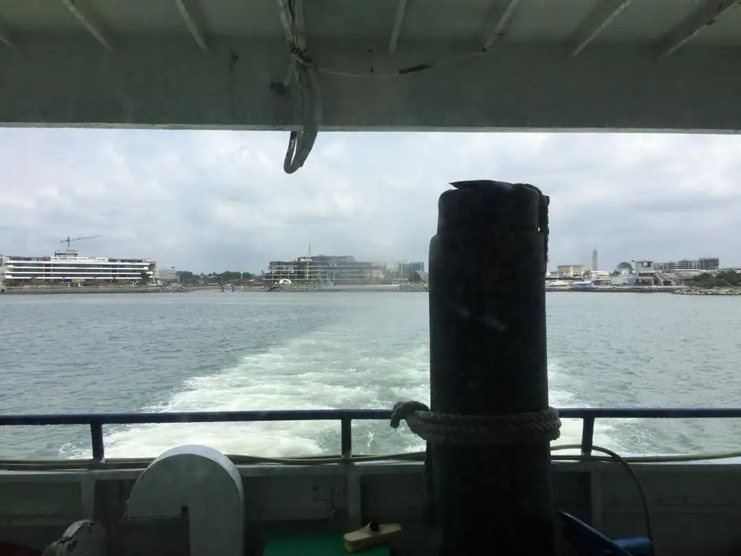Vue depuis un bateau assurant la traversée entre Port-Gentil et Omboué, avec le front de mer de Port-Gentil visible à l’arrière-plan au Gabon.