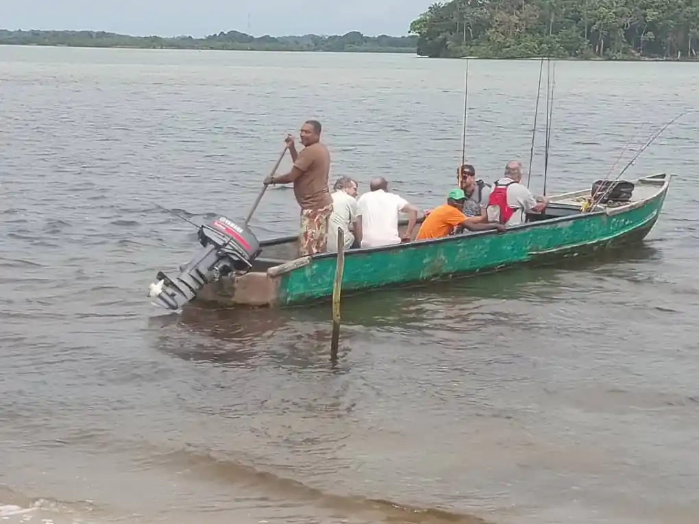 Pêcheurs à bord d’une pirogue motorisée avec leurs cannes, au départ pour une sortie de pêche sur la lagune d’Iguéla.