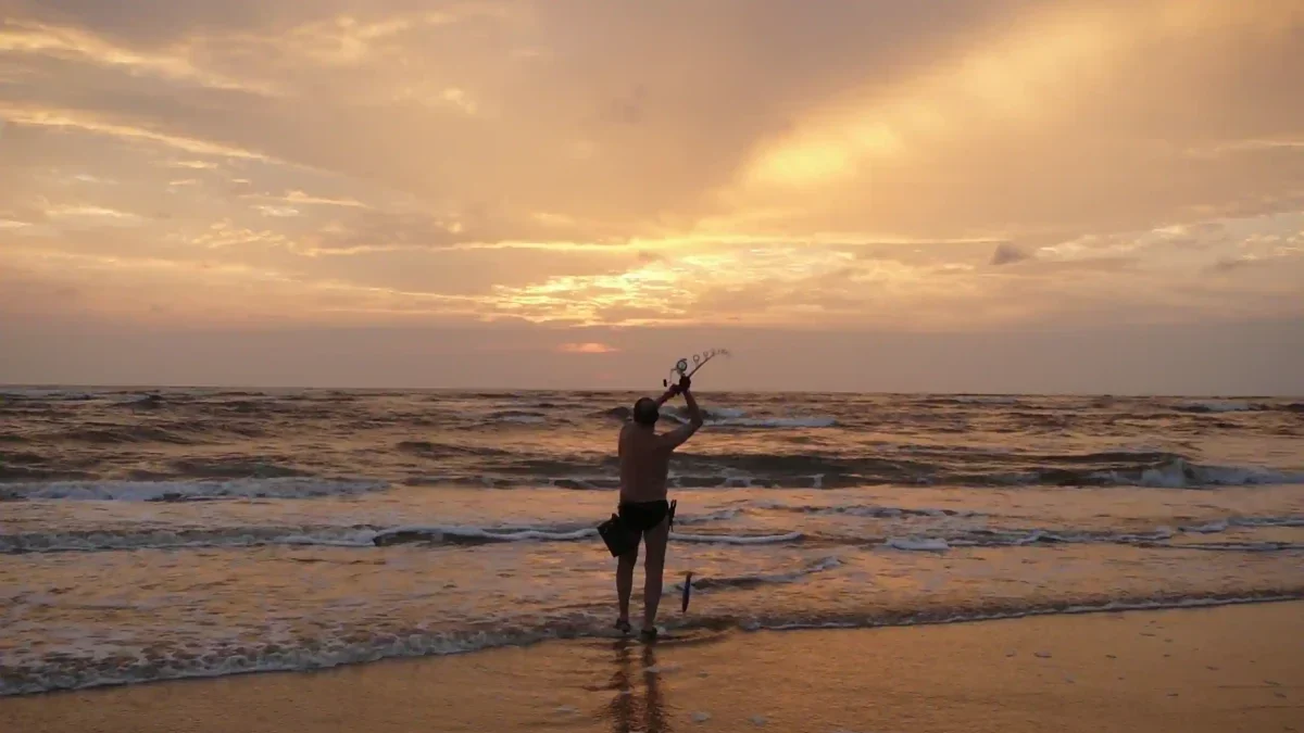 Pêcheur lançant sa ligne en surfcasting au coucher du soleil sur la plage d'Iguéla, au Gabon.