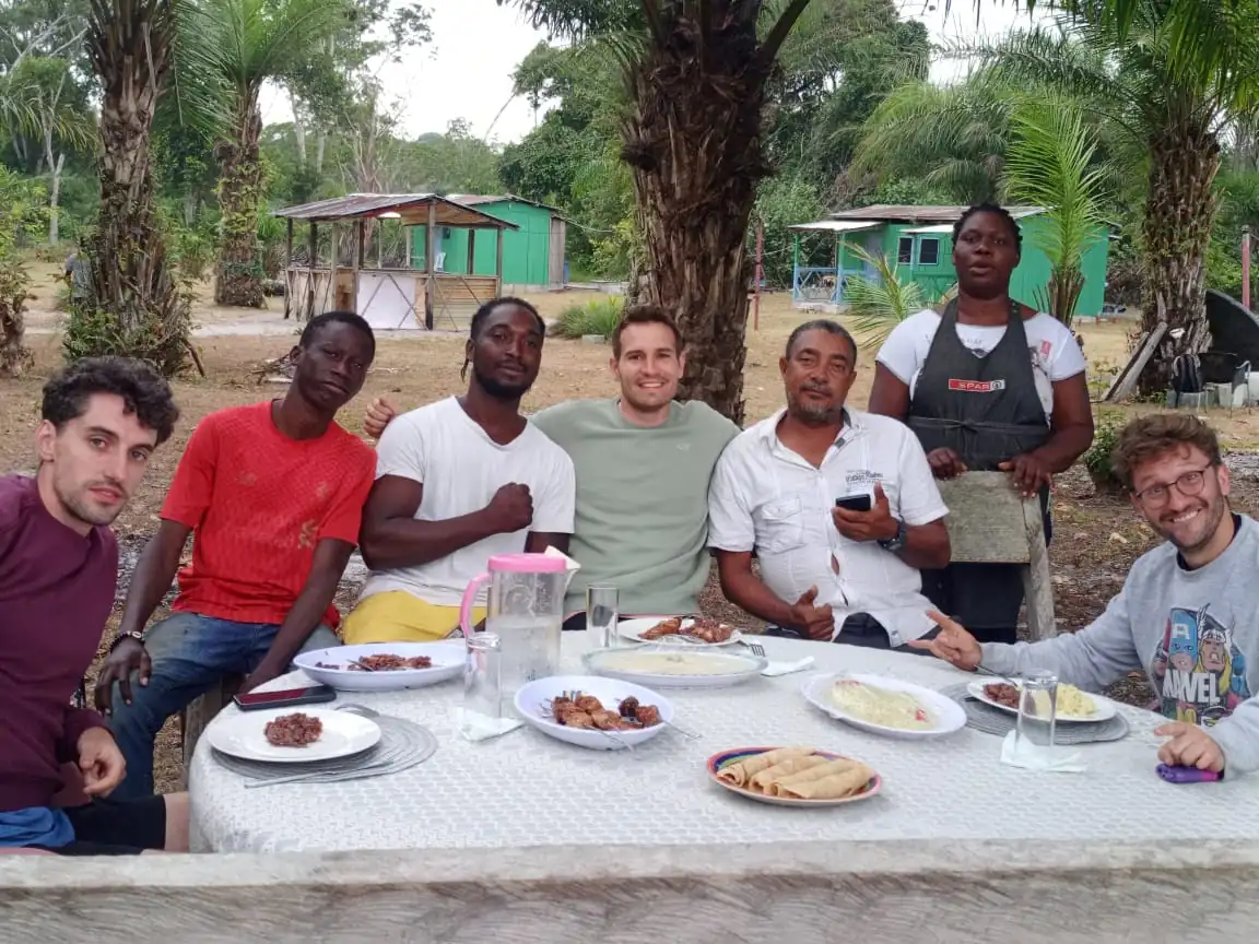 Pêcheurs et membres de l’équipe réunis autour d’un repas en plein air à Bangué Lodge, dans un cadre tropical.